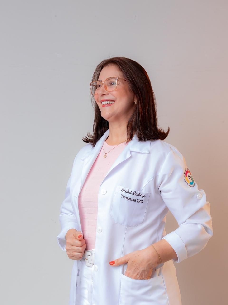 Isabel Bachega, terapeuta TRG, sorrindo de jaleco branco
